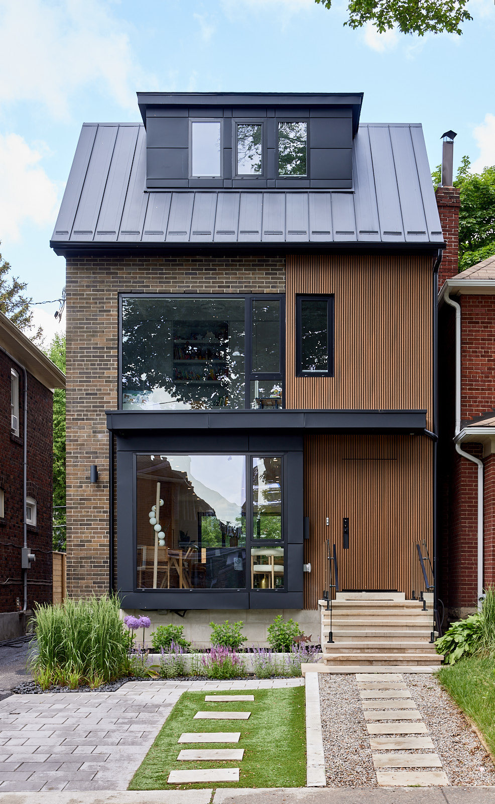 Narrow modern city home with dark metal detailing, vertical wood slats and large windows